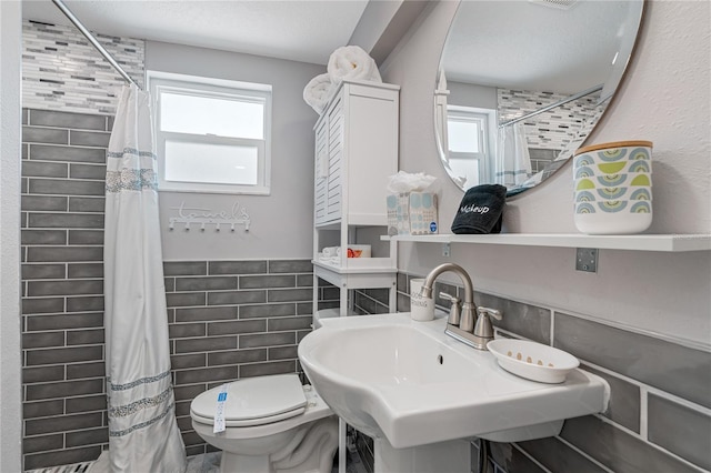 bathroom with sink, tile walls, a shower with shower curtain, a textured ceiling, and toilet