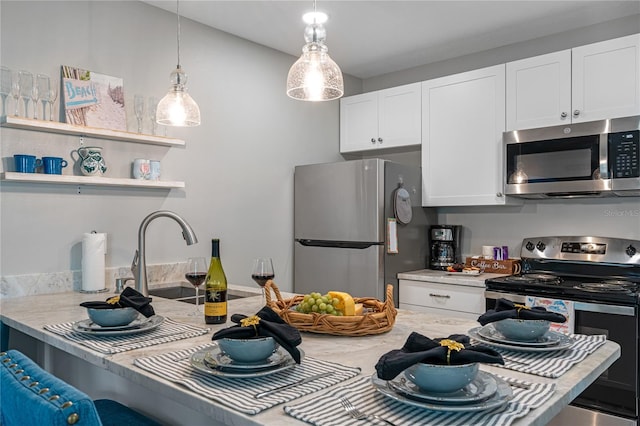 kitchen featuring decorative light fixtures, sink, a breakfast bar area, white cabinets, and stainless steel appliances