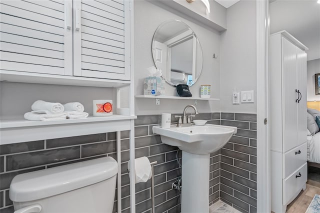 bathroom with hardwood / wood-style flooring, tile walls, and toilet