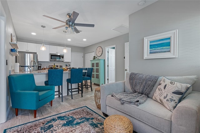 living room with ceiling fan and light hardwood / wood-style floors