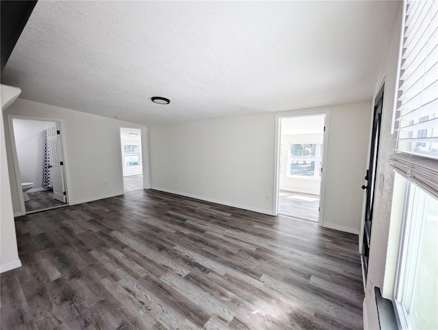 unfurnished room featuring dark wood-type flooring and a textured ceiling