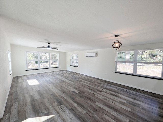 unfurnished living room with a wall mounted air conditioner, dark wood-type flooring, and ceiling fan