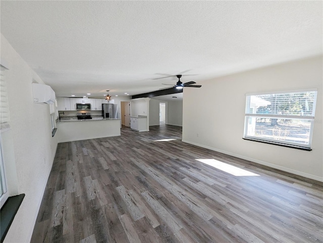 unfurnished living room with ceiling fan with notable chandelier, hardwood / wood-style floors, and a textured ceiling