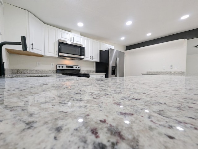 kitchen featuring white cabinetry, stainless steel appliances, and light stone countertops