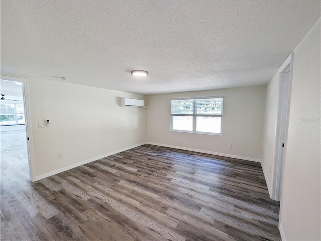 spare room with a textured ceiling, dark hardwood / wood-style floors, and a wall mounted AC