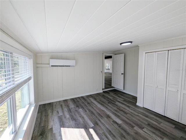 unfurnished bedroom with dark hardwood / wood-style floors and an AC wall unit