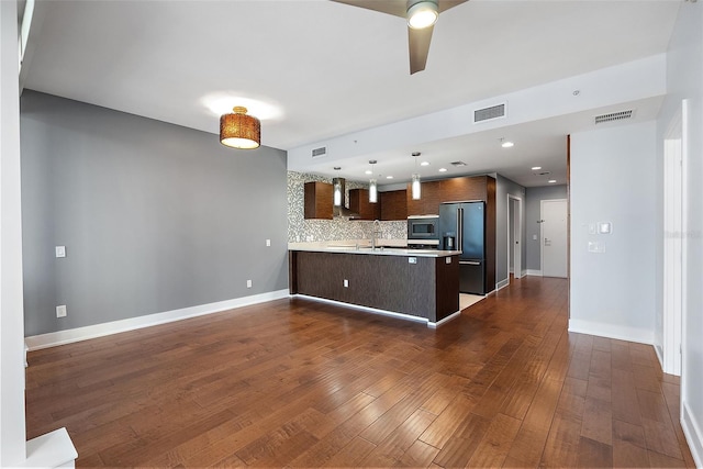 kitchen with dark hardwood / wood-style floors, stainless steel microwave, tasteful backsplash, kitchen peninsula, and high end fridge