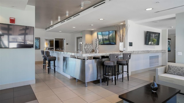 kitchen with light tile patterned flooring, a large island, light stone counters, and a kitchen breakfast bar