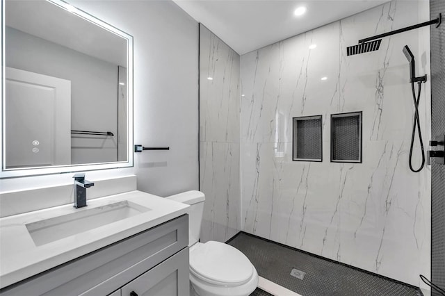 bathroom featuring tiled shower, vanity, and toilet