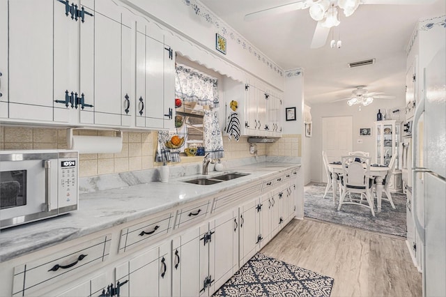 kitchen with sink, light hardwood / wood-style flooring, light stone countertops, and white cabinets