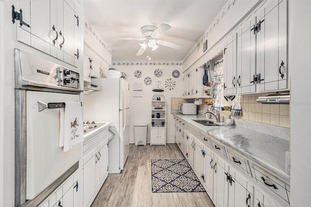 kitchen with sink, oven, white cabinets, ceiling fan, and light hardwood / wood-style flooring