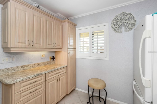 kitchen featuring light brown cabinetry, ornamental molding, white fridge, light tile patterned floors, and light stone counters