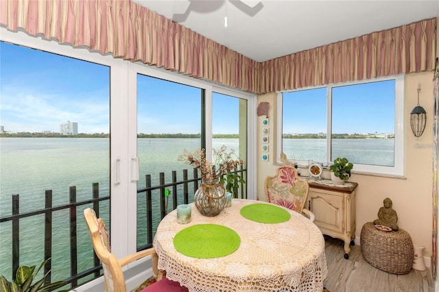 sunroom featuring ceiling fan and a water view