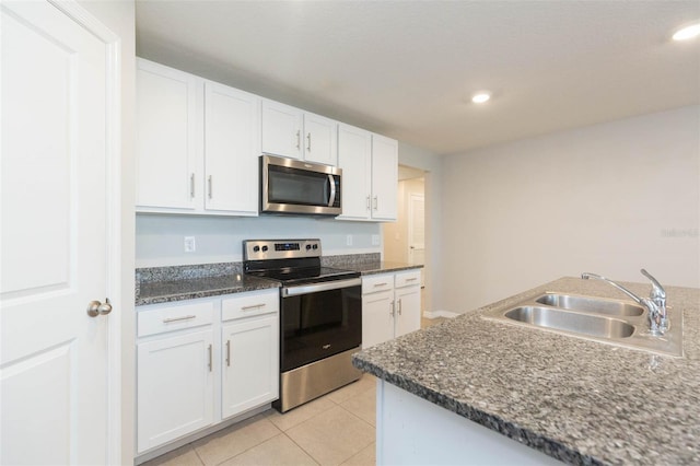 kitchen featuring sink, white cabinetry, light tile patterned floors, appliances with stainless steel finishes, and dark stone counters