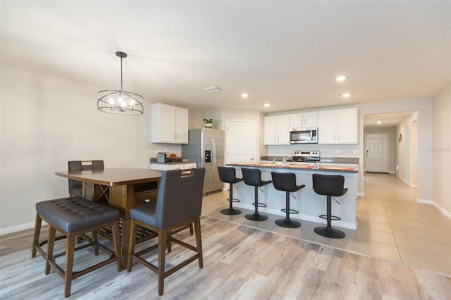 kitchen with a kitchen breakfast bar, a center island, white cabinets, and appliances with stainless steel finishes