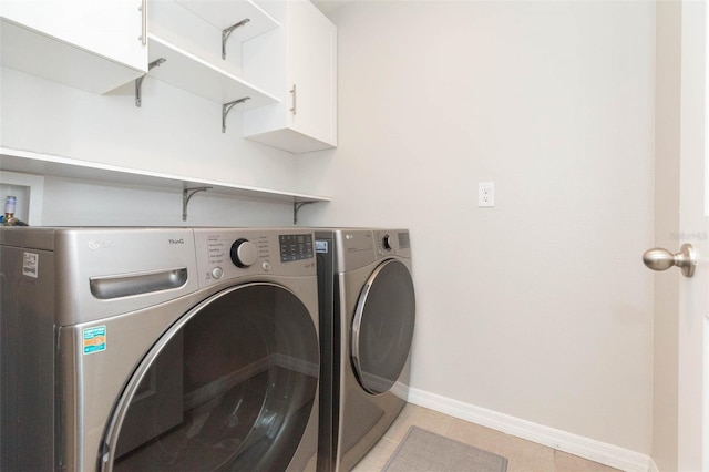 washroom with independent washer and dryer, light tile patterned floors, and cabinets