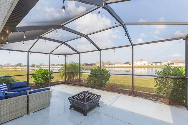 view of patio / terrace featuring a water view, a lanai, and an outdoor living space with a fire pit