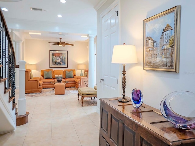 hallway with light tile patterned floors, ornamental molding, and decorative columns