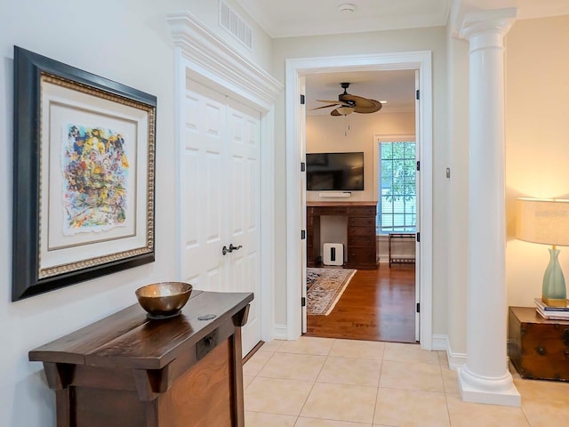 hallway with light tile patterned flooring, ornamental molding, and decorative columns