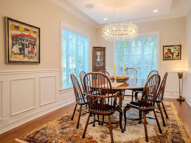 dining space with crown molding, wood-type flooring, and a notable chandelier