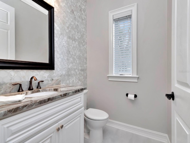 bathroom featuring vanity, toilet, and backsplash