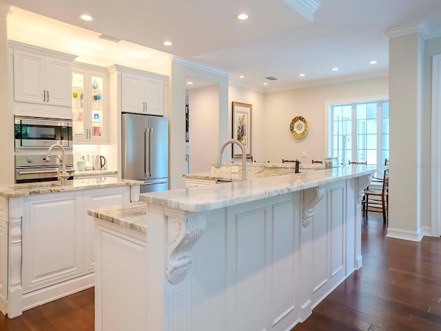 kitchen with dark wood-type flooring, ornamental molding, stainless steel appliances, a large island, and white cabinets