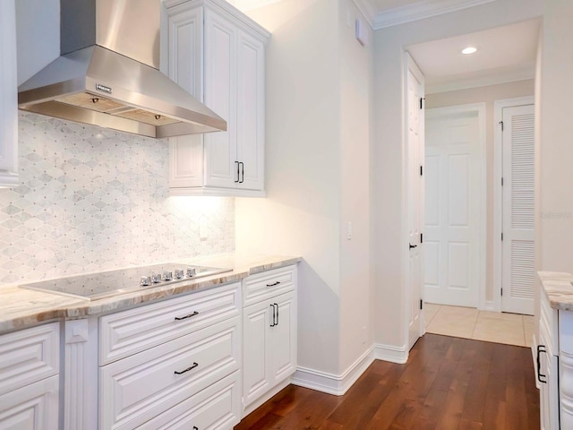 kitchen featuring white cabinetry, black cooktop, light stone counters, and wall chimney range hood