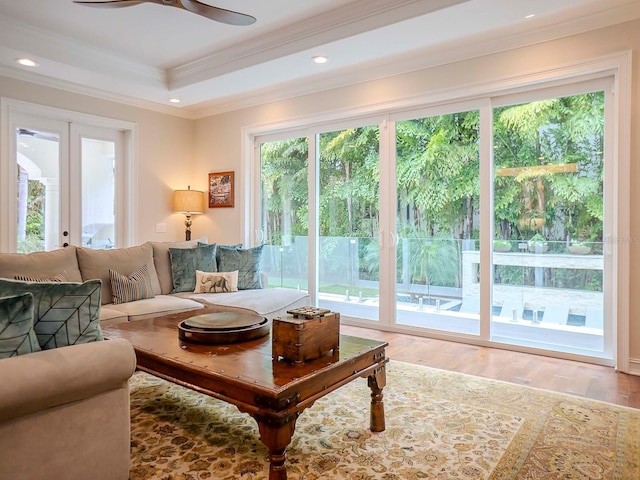 living room with hardwood / wood-style flooring, ceiling fan, a tray ceiling, crown molding, and french doors