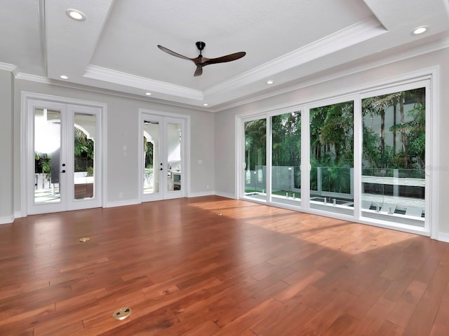 unfurnished living room with wood-type flooring, ornamental molding, french doors, and a raised ceiling