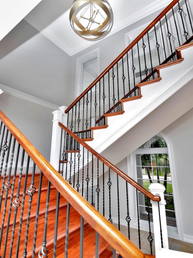 staircase with hardwood / wood-style flooring, ornamental molding, and a high ceiling