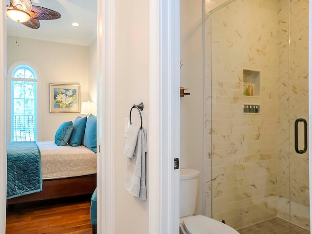 bathroom featuring toilet, a shower with shower door, ornamental molding, ceiling fan, and hardwood / wood-style floors