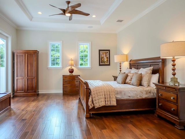 bedroom with multiple windows, dark hardwood / wood-style floors, and a tray ceiling