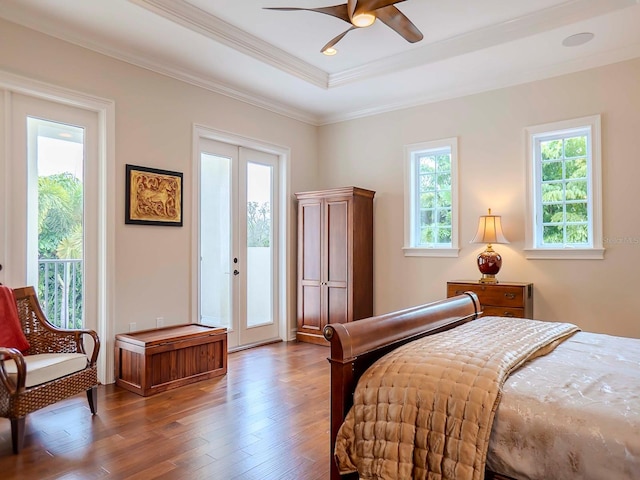 bedroom featuring french doors, crown molding, access to outside, a raised ceiling, and hardwood / wood-style floors