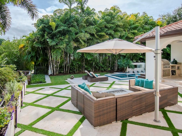 view of patio with an in ground hot tub, an outdoor kitchen, and an outdoor living space with a fire pit