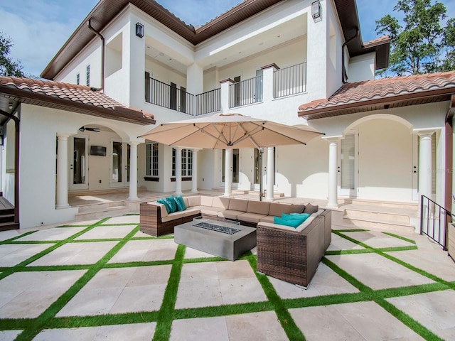 back of house with an outdoor living space with a fire pit and a patio