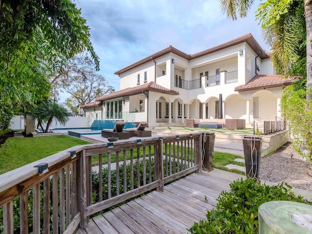 back of property with a pool side deck, a balcony, and an outdoor hangout area