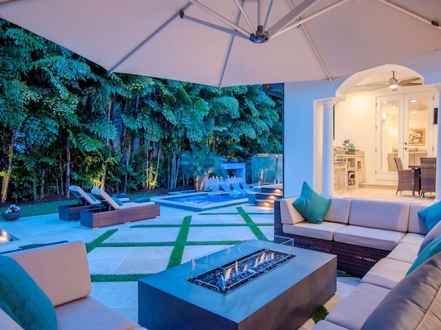 view of patio / terrace featuring ceiling fan and an outdoor living space with a fire pit