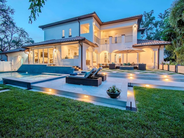 back of house with a balcony, an outdoor living space, a pool with hot tub, and a patio area