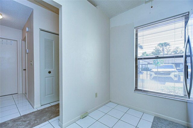 unfurnished room featuring a textured ceiling and light tile patterned floors