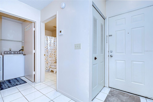 bathroom with washing machine and dryer, tile patterned floors, and toilet