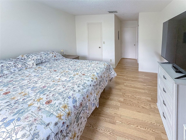 bedroom with a textured ceiling and light wood-type flooring