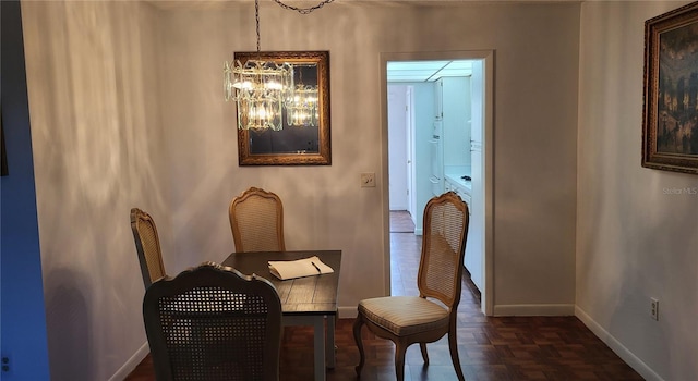 dining area featuring dark parquet flooring and a notable chandelier