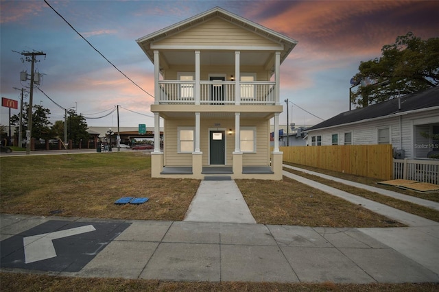 view of front of property with a balcony, covered porch, and a lawn