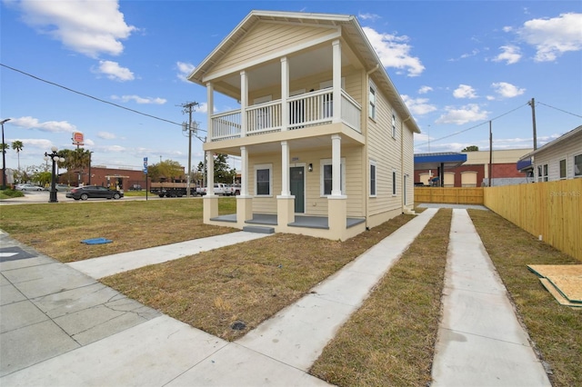 view of front of house featuring a balcony, a porch, and a front yard