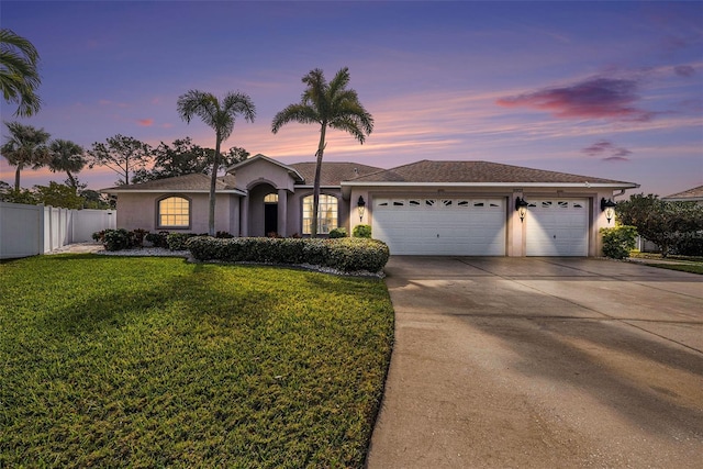 single story home featuring a garage and a lawn