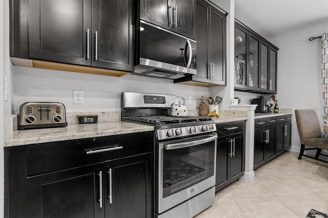 kitchen with light tile patterned floors, light stone countertops, and appliances with stainless steel finishes