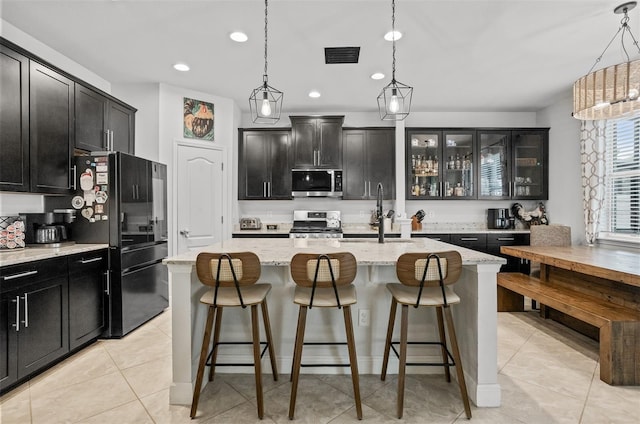 kitchen with pendant lighting, sink, a kitchen island with sink, stainless steel appliances, and light stone counters