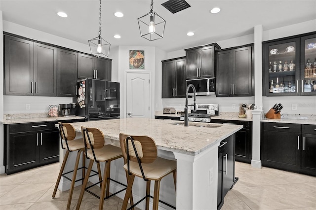 kitchen with decorative light fixtures, sink, and a center island with sink