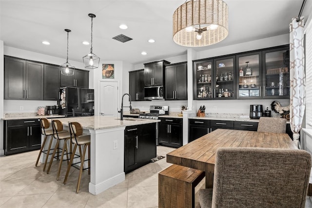 kitchen featuring pendant lighting, sink, a kitchen breakfast bar, stainless steel appliances, and an island with sink