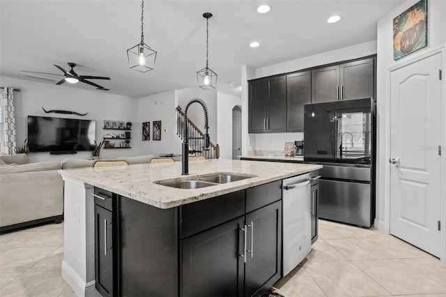 kitchen with pendant lighting, sink, appliances with stainless steel finishes, light stone countertops, and an island with sink